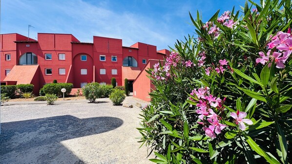 A red building with multiple windows and a gravel driveway.