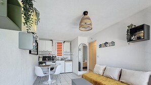 Un espace de vie compact comprenant un coin cuisine, un espace repas et un canapé.