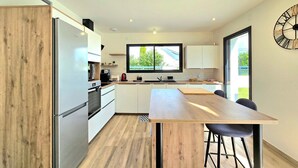 Una cocina moderna con armarios blancos, una mesa de madera y un amplio ventanal.