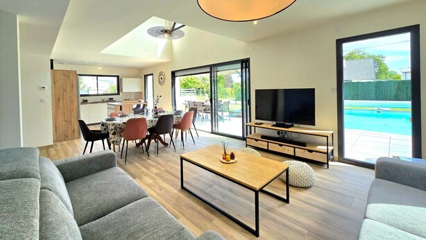 Una sala moderna con comedor, televisor y vista a la piscina.