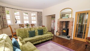 A living room with a green sofa, a fireplace, and a dining area with chairs and a table.