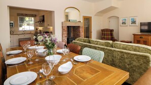 A dining area with a wooden table set for a meal, a sofa, and a television in the background.