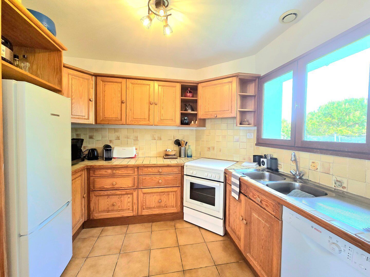 A kitchen with wooden cabinets, a Bosch dishwasher, a stove, and a sink.