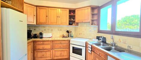 A kitchen with wooden cabinets, a Bosch dishwasher, a stove, and a sink.