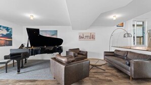 Una sala de estar con un piano de cola, un sofá, una mesa de centro y un cuadro en la pared.