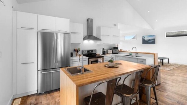 Una cocina moderna con una isla central, electrodomésticos de acero inoxidable y un techo alto.