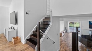 Un interior moderno con una escalera, un televisor de pantalla plana y suelo de madera.