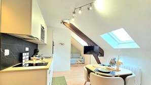 A modern kitchen with a built-in microwave, a wooden countertop, and a black backsplash. There is a dining area with a round table and chairs, and a skylight above. - A pas de tout, historic center, train, parking (Vannes)