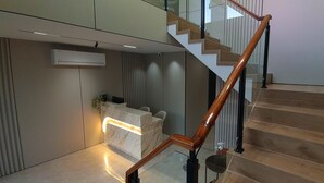 Een modern receptiebalie met een marmeren afwerking, een houten trap met glazen balustrades en een luchtverwarmingsunit aan de muur.