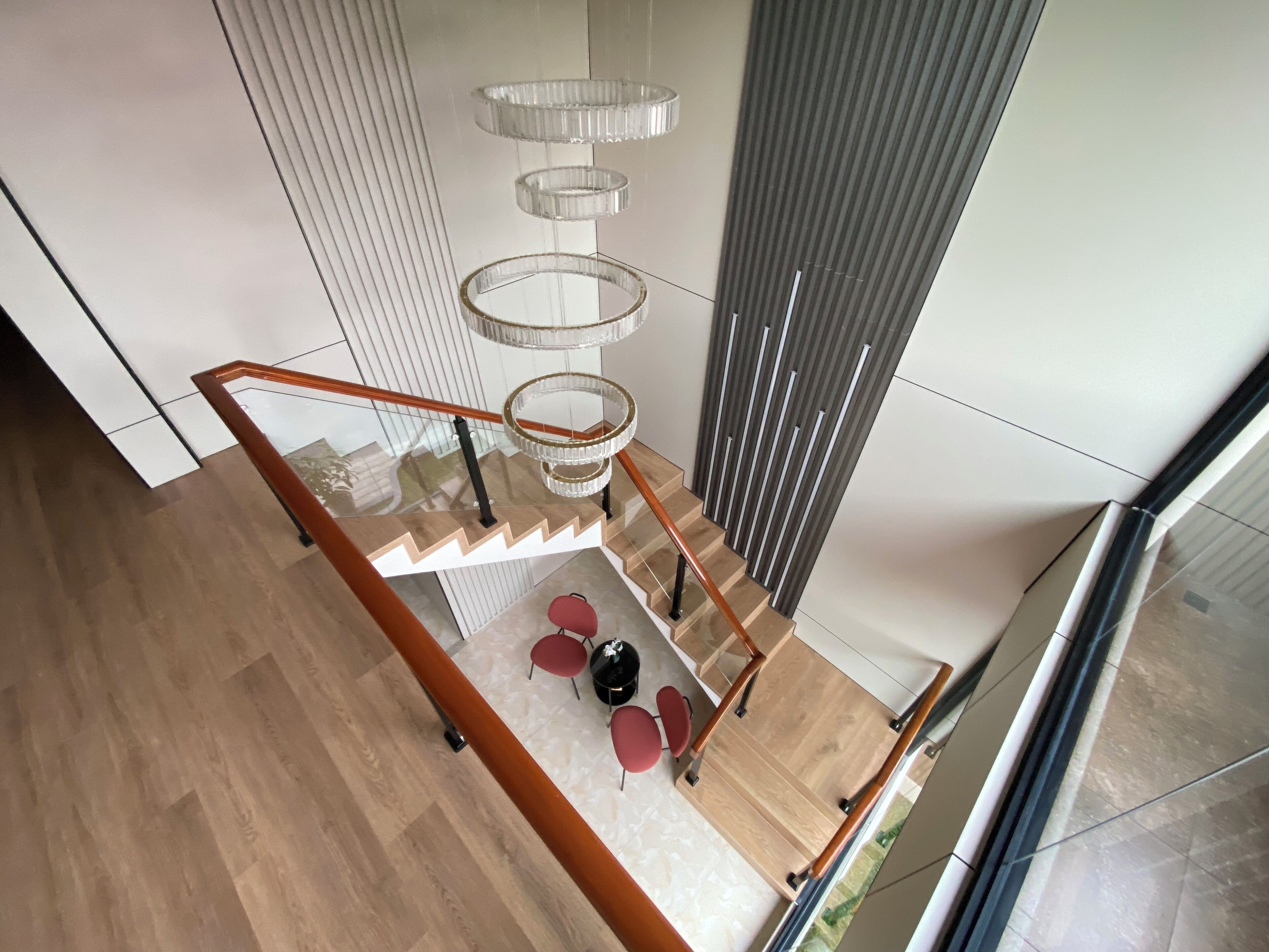 A modern staircase with a glass railing and a wooden floor.