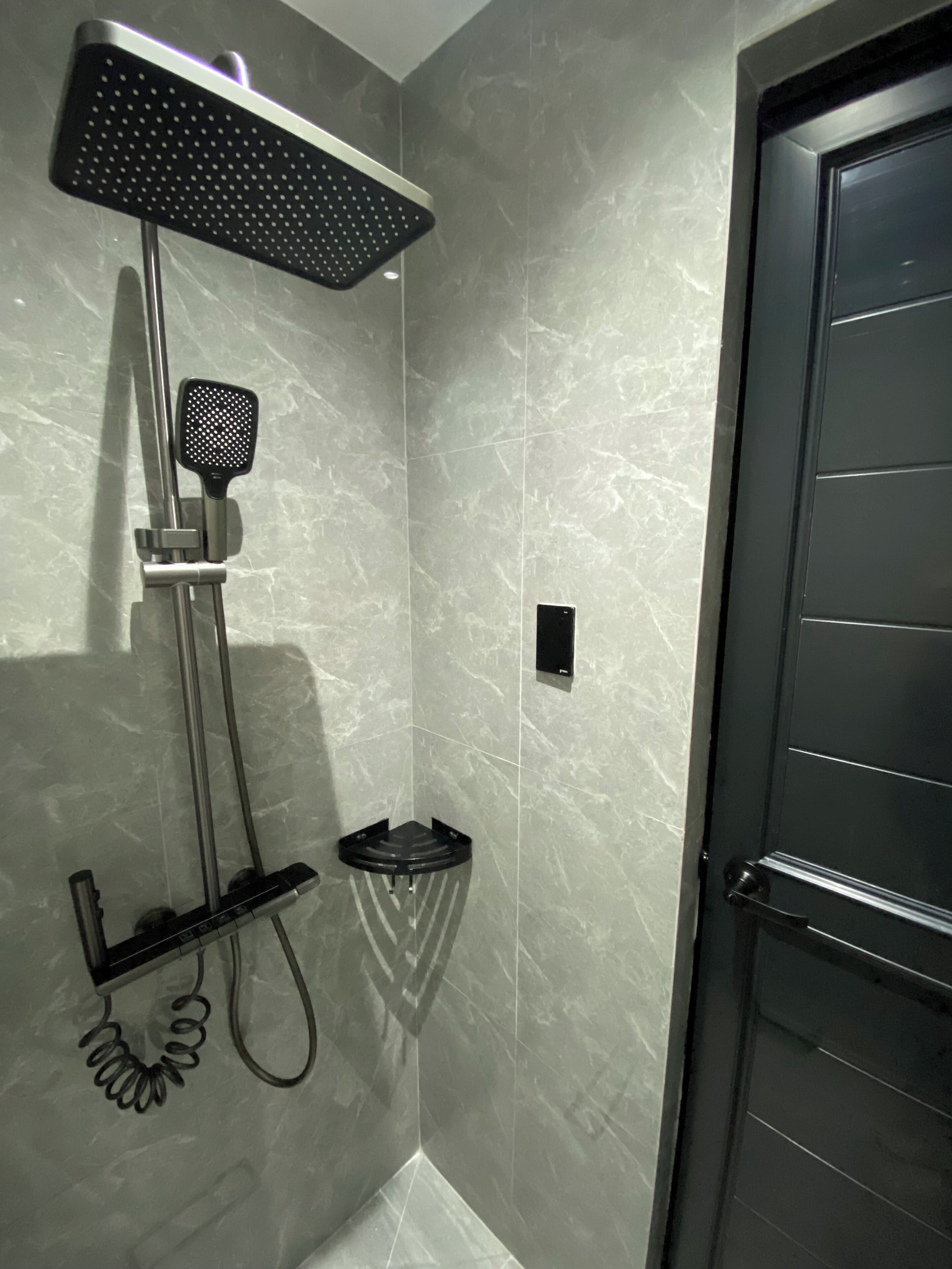 A modern bathroom with a shower, a handheld showerhead, and a handheld massager.