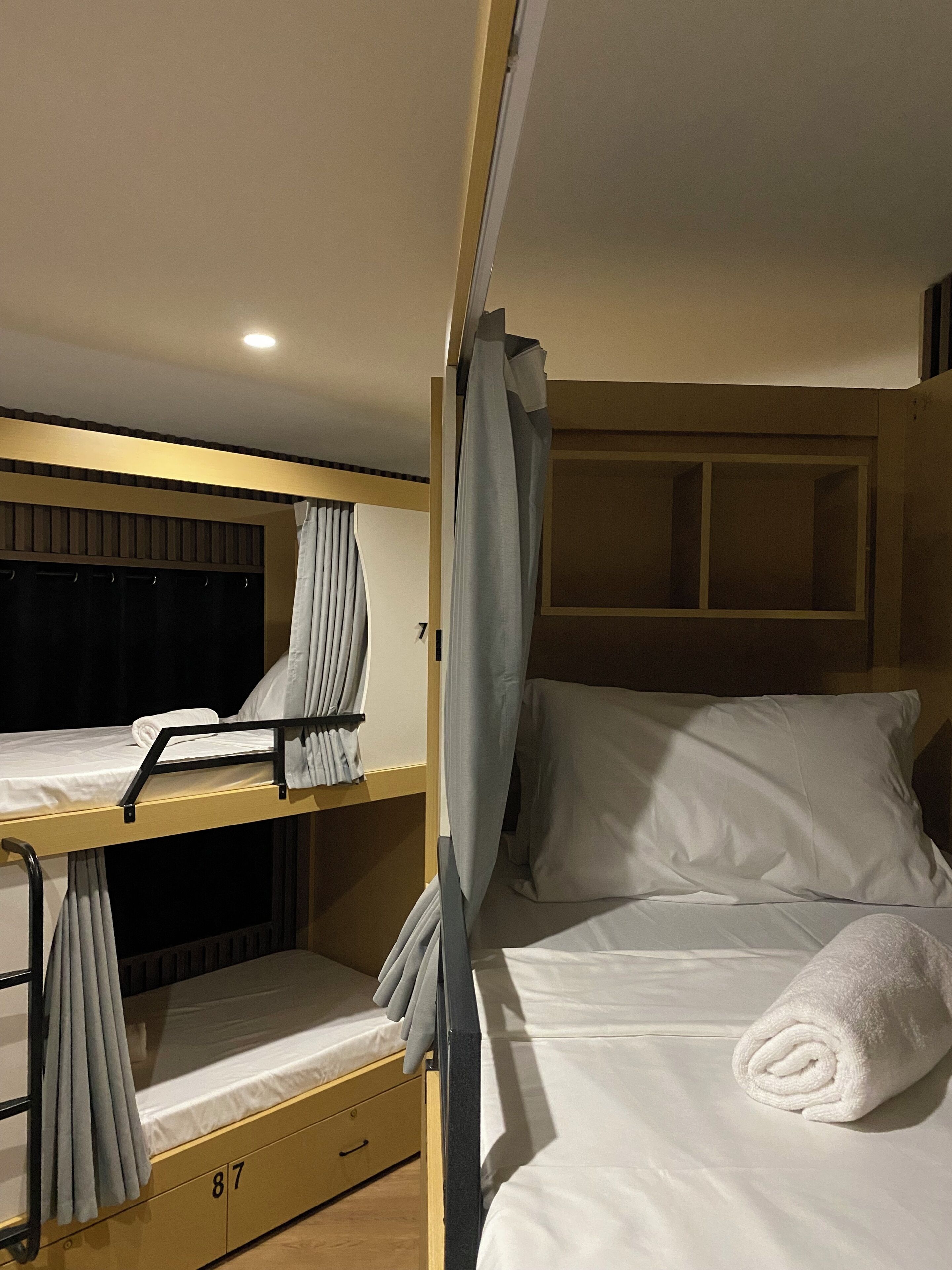 A bunk bed room with a curtain, a window, and a towel on the bed.