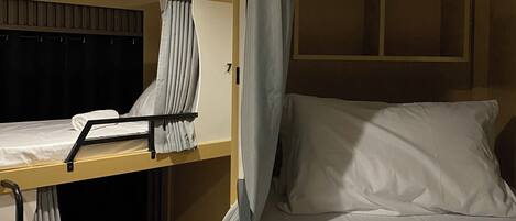 A bunk bed room with a curtain, a window, and a towel on the bed.