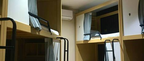 A dormitory room with bunk beds, wooden flooring, and curtains.