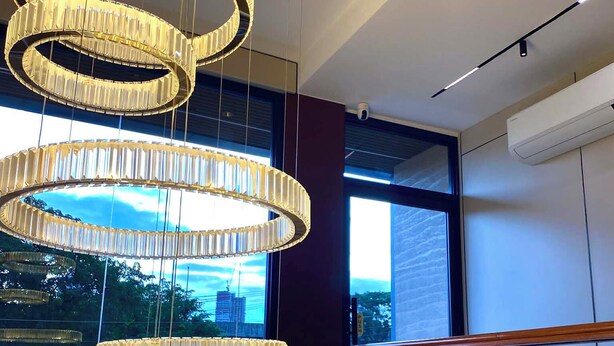 Een modern interieur met een grote, ronde kroonluchter, een glazen balustrade en uitzicht buiten door grote ramen.