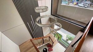 Een modern interieur met een spiltrap, een hangende kroonluchter en uitzicht op de straat.