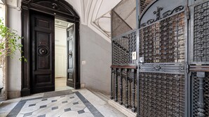 A hallway with a black door, a metal gate, and a patterned floor. - Palazzo Guida al Duomo (Naples)