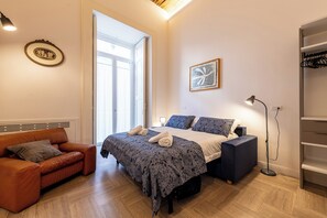 Een slaapkamer met een bed, een sofa, een staande lamp en een kledingkast.