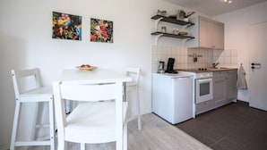 Une cuisine moderne avec des meubles blancs, un îlot central et deux tableaux représentant des fleurs, accrochés au mur.