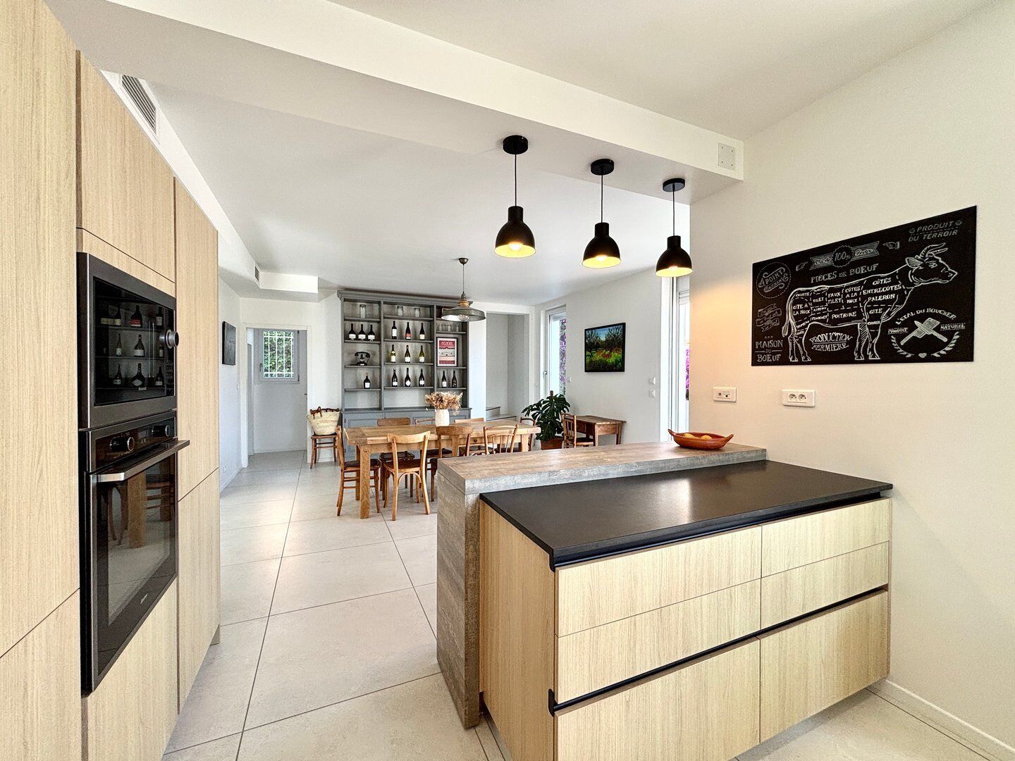 Een moderne keuken met een centraal eiland, houten kastjes en hanglampen.