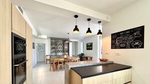 Une cuisine moderne dotée d’un îlot central, de meubles en bois et de luminaires suspendus.