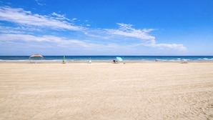 Une vaste plage de sable fin, avec un ciel dégagé et une mer calme.