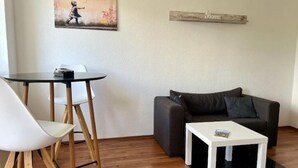 A small living area with a round table, two white chairs, a dark grey sofa, and a white coffee table.