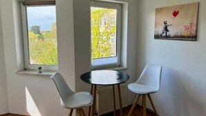 A room with two windows, a radiator, and a table with two chairs.