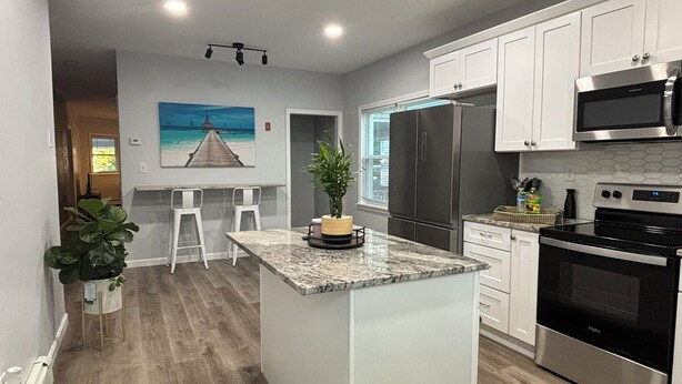 A modern kitchen with white cabinets, stainless steel appliances, and a central island.