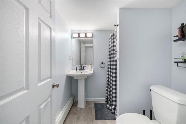 A bathroom with a white sink, a toilet, and a shower curtain. - Spacious & Stylish 5 -bed 2 bath house in charming Providence, a block from PC (Providence)