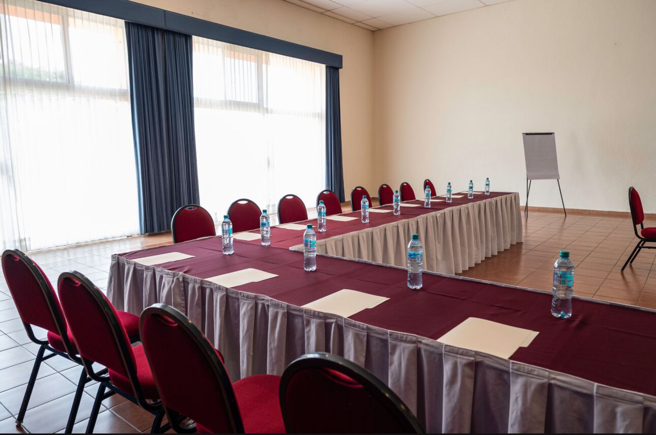 A conference room with a long table, red chairs, water bottles, and a whiteboard.