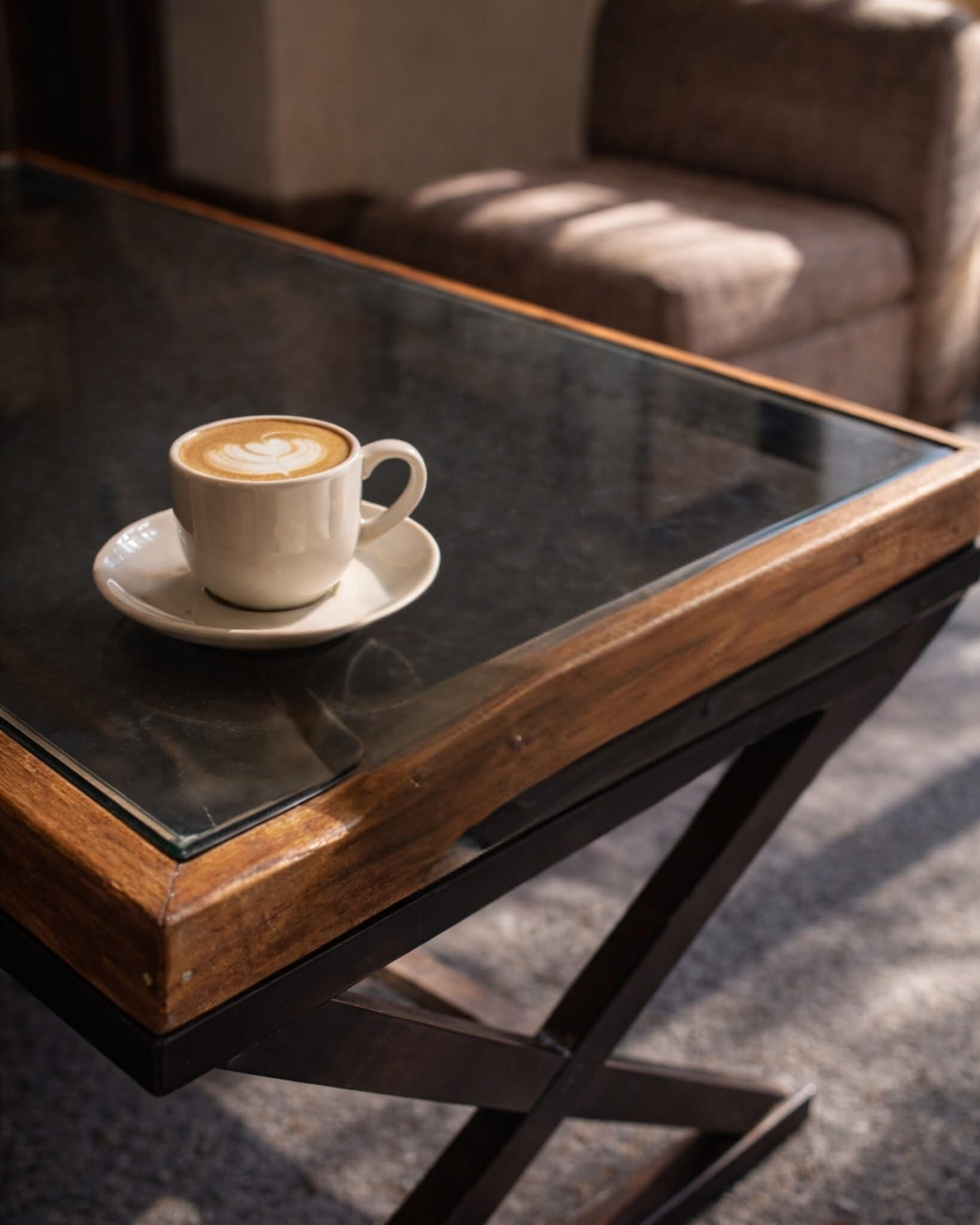 Una taza de café sobre una mesa de vidrio con un marco de madera.