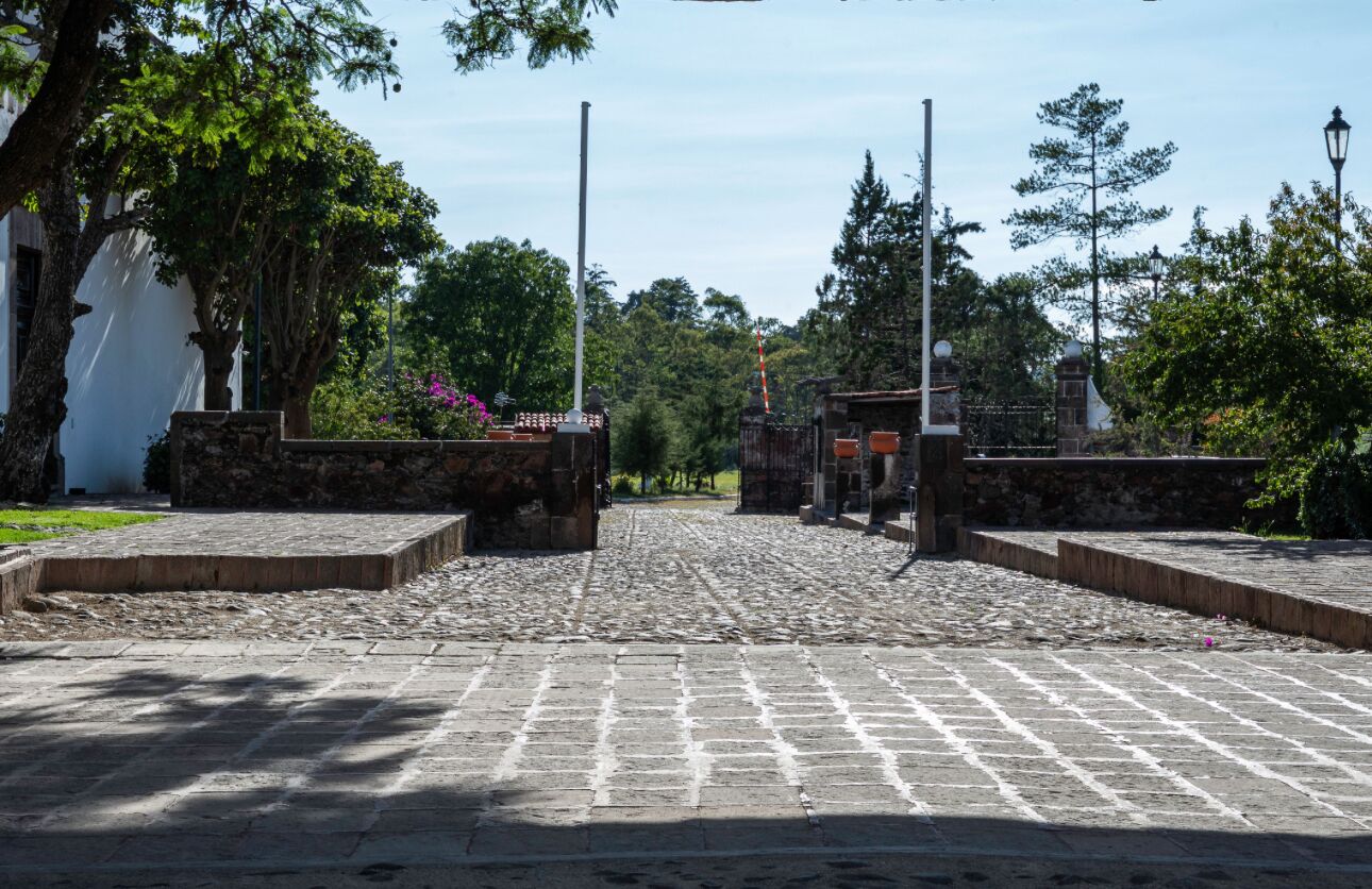 Un sentier pavé de pierres menant à un bâtiment historique aux murs de pierre et à la façade blanche.