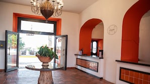A lobby with a large potted plant, a reception desk, and a clock on the wall. - Hotel Hacienda La Muralla (Amealco)
