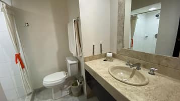 A bathroom with a toilet, sink, mirror, and tiled floor.