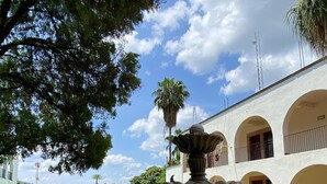 A courtyard with a fountain, surrounded by greenery and a building with arched balconies. - Hotel Hacienda de Jalpan (Jalpan de Serra)