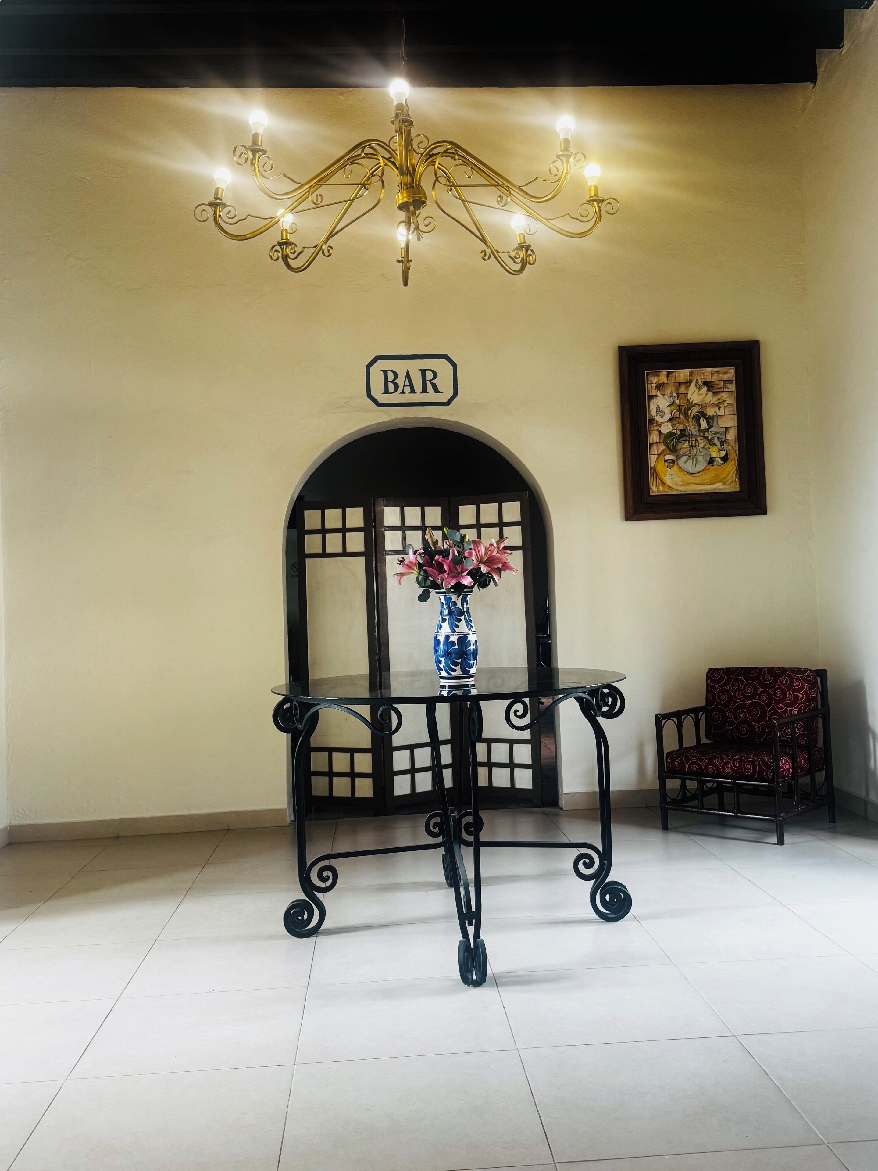 Un área de bar con un letrero, un jarrón decorativo, una silla y una araña.