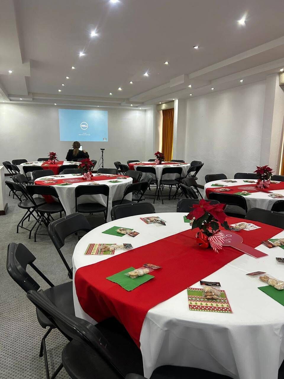 A conference room with round tables, black chairs, and red tablecloths.