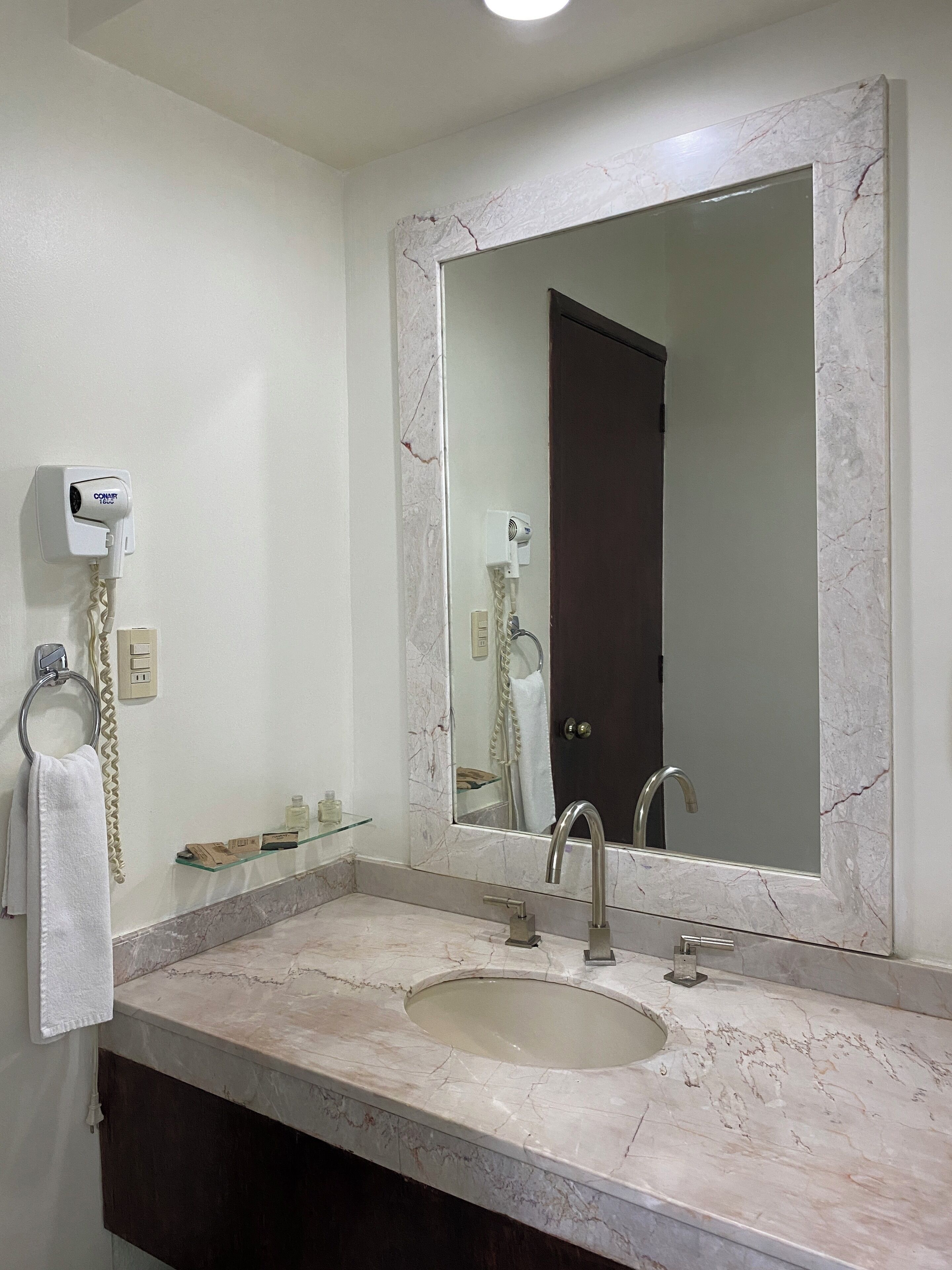 A bathroom with a marble sink, a large mirror, and a towel ring.