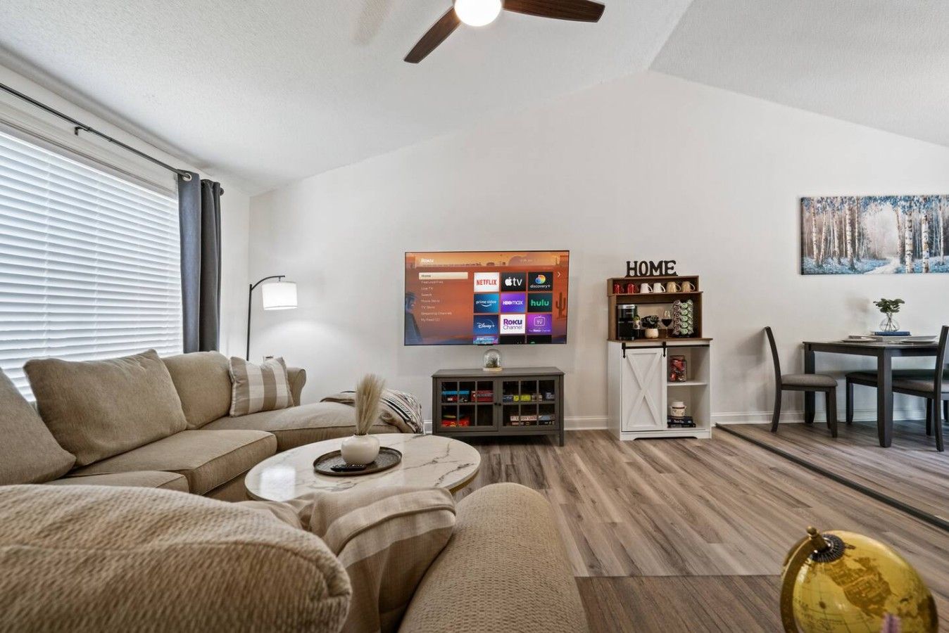 Ein modernes Wohnzimmer mit einer Couch, einem Couchtisch und einem an der Wand befestigten Flachbildfernseher.