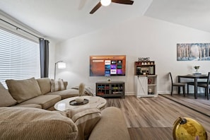 A modern living room with a sofa, coffee table, and a flat-screen TV mounted on the wall.