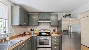 A kitchen with a stainless steel refrigerator, an oven, and a sink. - Near Carowinds ~ 4BR w/ Game Room & Splash Pad (Pineville)