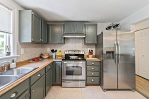 A kitchen with grey cabinets, a stainless steel refrigerator, and a built-in oven.