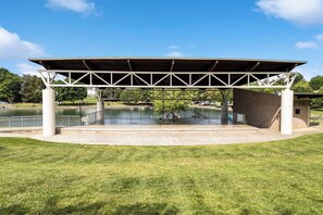 A covered outdoor area with a pool, surrounded by grass and trees.
