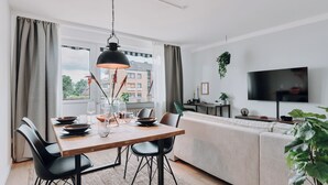 Una sala de estar moderna con comedor, ventanas grandes, televisor y sofá.