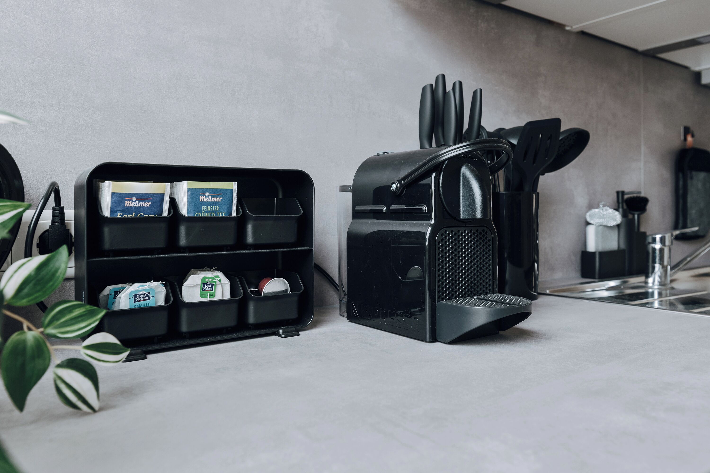 A kitchen counter with a coffee machine, a knife holder, and a shelf with packaged goods.