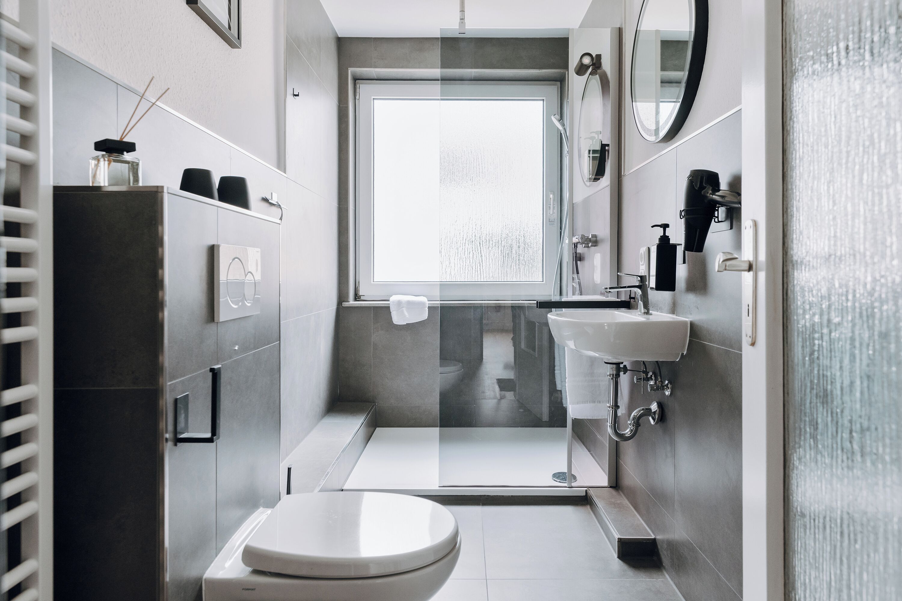 Un baño moderno con inodoro, lavamanos y ducha.