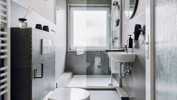 Un baño moderno con inodoro, lavamanos y ducha.