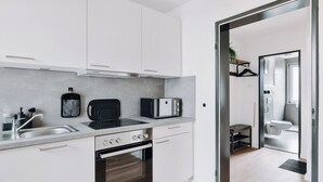 Una cocina moderna con armarios blancos, horno integrado, microondas y pileta.
