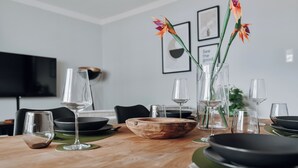 Una mesa de comedor dispuesta con cubiertos de vidrio transparente, un tazón de madera y salvamanteles verdes.